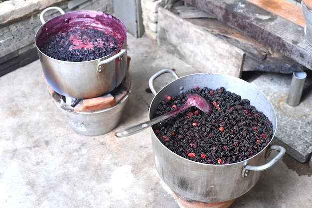 Faire bouillir la confiture de mûres dans une casserole en métal sur feu ouvert