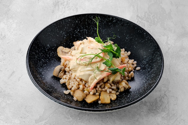 Faire bouillir de l'orge perlé avec des champignons frits et une sauce crémeuse à la farine sur une assiette