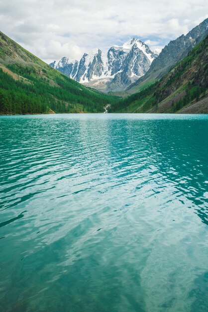 Photo faire briller l'eau dans le lac de montagne dans les hautes terres. magnifiques montagnes enneigées géantes. le ruisseau coule du glacier. blanche neige claire sur la crête. magnifique paysage atmosphérique de la nature majestueuse de l'altaï.