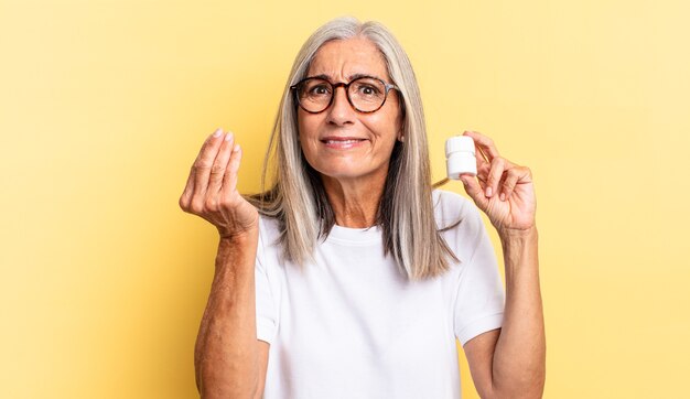 Faire capice ou geste d'argent, vous dire de payer vos dettes ! et tenant une bouteille de pilules