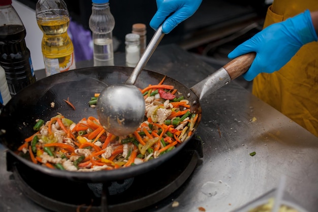 faire cuire des frites de légumes dans une poêle à wok en feu Le chef remue des légumes dans un wok