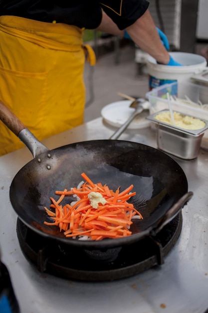 faire cuire des frites de légumes dans une poêle à wok en feu Le chef remue des légumes dans un wok