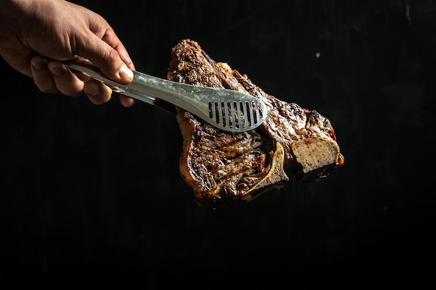 Faire cuire la main avec un gros morceau de viande de bœuf fraîche préparée sur un gril