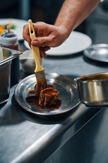 Faire cuire un steak de peinture avec de la sauce dans une cuisine professionnelle