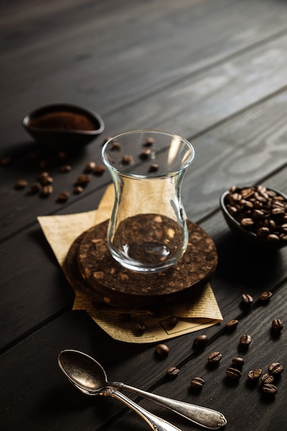 Faire du café à cezve. Des grains, du café moulu, un verre vide, une cuillère. Toile de fond en bois.