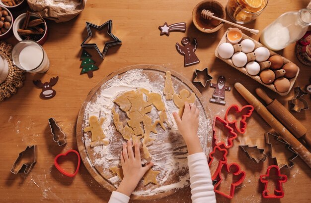 Faire du pain d'épice à la maison petite fille couper des biscuits de pâte de pain d'epice noël et la nouvelle année