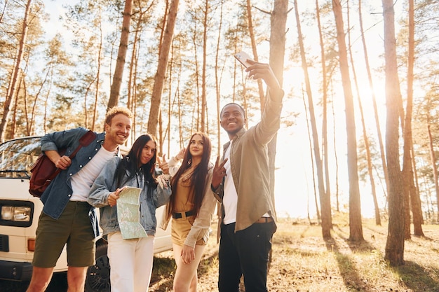 Faire du selfie Un groupe de jeunes voyage ensemble dans la forêt pendant la journée