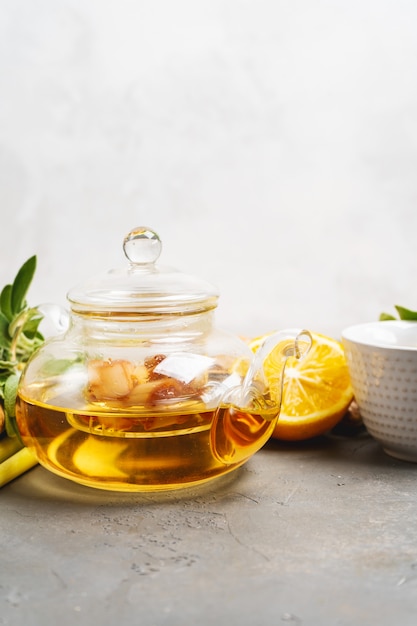 Faire du thé au gingembre antioxydant et anti-inflammatoire sain avec du gingembre frais, de la citronnelle, de la sauge, du miel et du citron sur fond sombre avec un espace de copie.