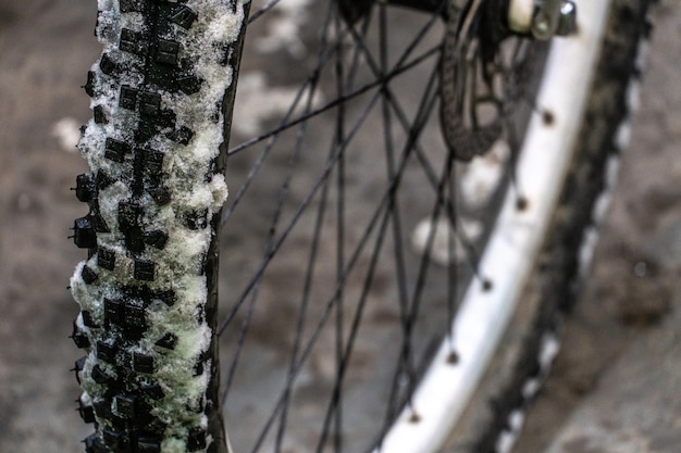 Faire du vélo en hiver Pneu de vélo recouvert de neige Vélo dans l'atelier pour réparation Gros plan sur la roue avant et la neige Grandes pointes sur un pneu épais