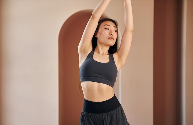 Faire des exercices de remise en forme Jeune femme asiatique sérieuse debout à l'intérieur