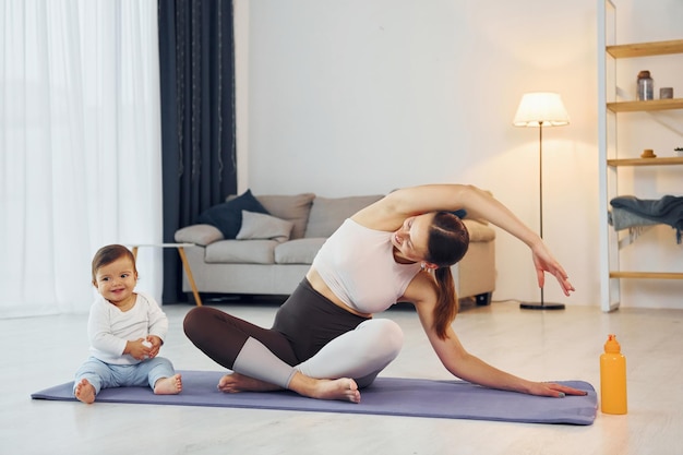 Faire des exercices de yoga Mère avec sa petite fille est à la maison ensemble