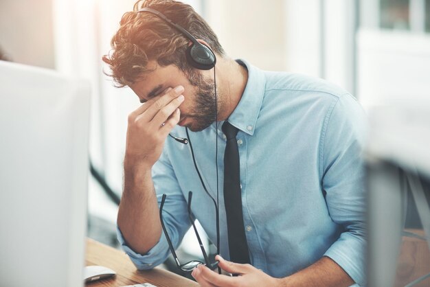 Faire face à des clients difficiles Photo d'un jeune homme stressé alors qu'il travaillait dans un centre d'appels