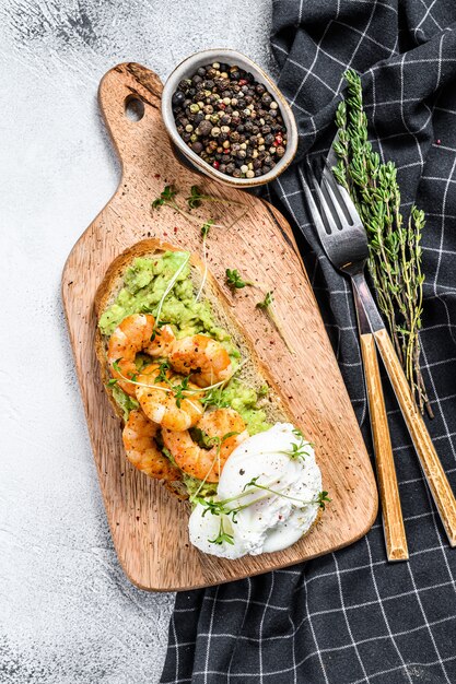 Faire griller les crevettes, les crevettes, l'avocat et l'oeuf poché. Fond gris.