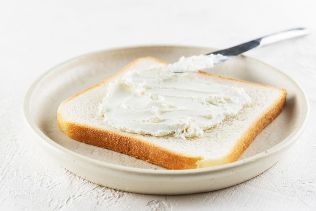 Faire griller du pain tartiné de fromage à la crème dans une assiette sur un tableau blanc