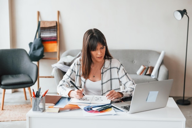 Faire de la paperasse Une jeune travailleuse indépendante est à l'intérieur de la maison pendant la journée