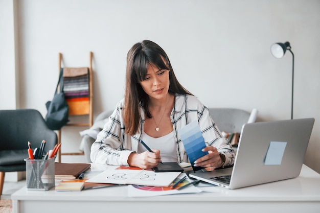 Faire de la paperasse Une jeune travailleuse indépendante est à l'intérieur de la maison pendant la journée