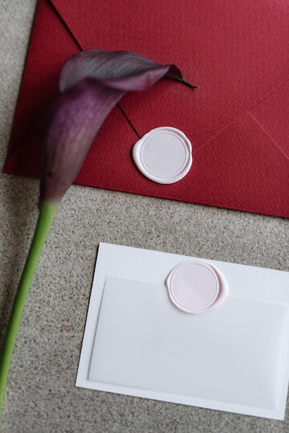 Faire-part de mariage dans une enveloppe grise sur une table avec des brins verts