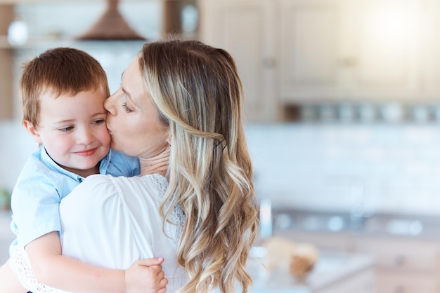 Faire partie d'une famille signifie sourire pour les photos. Plan d'une mère portant son fils dans le salon de la maison.