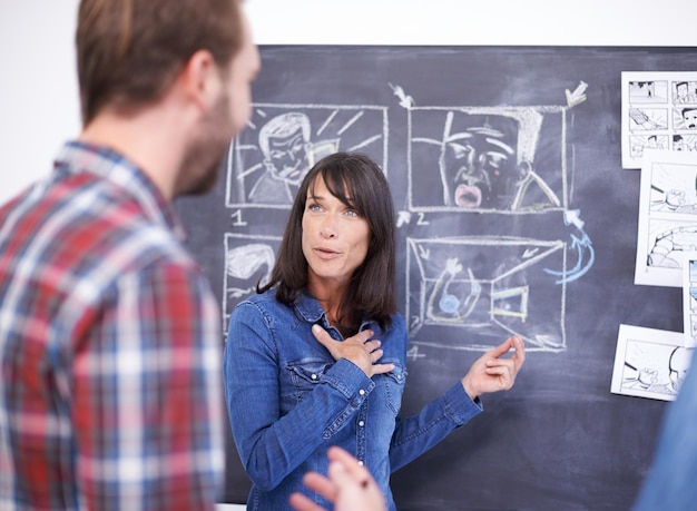 Faire passer ses idées Plan de deux collègues planifiant un storyboard sur un tableau noir