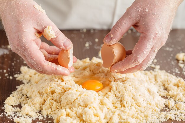 Faire de la pâte par les mains des hommes sur fond de table en bois