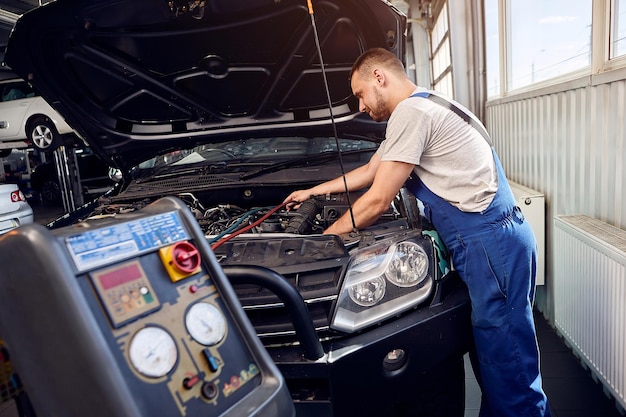 Faire le plein du climatiseur Un mécanicien pompe du fréon dans le système de climatisation lors d'un service de voiture