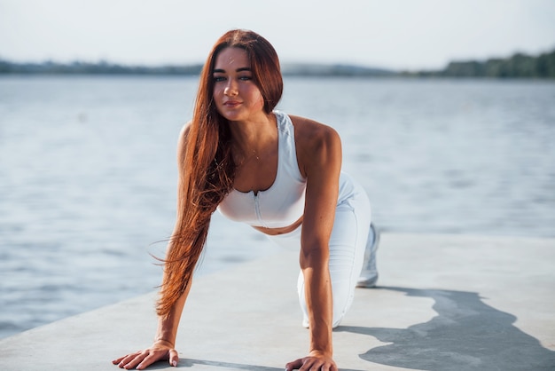 Faire des pompes. Plan d'une femme sportive faisant des exercices de fitness près du lac pendant la journée.