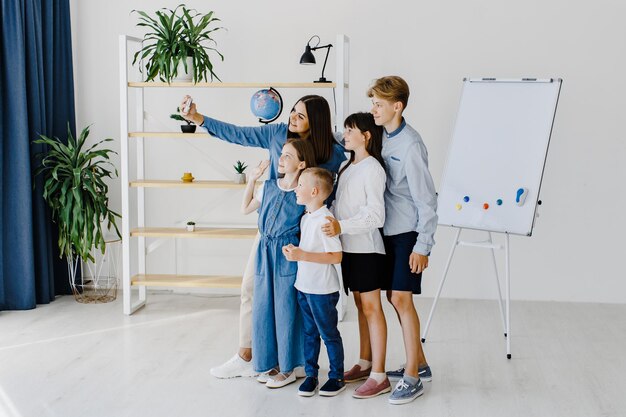 Faire un selfie par téléphone Groupe d'enfants étudiants en classe à l'école avec l'enseignant et s'amuser