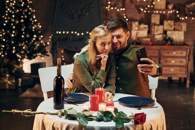 Faire selfie en utilisant le téléphone Un jeune couple charmant a un dîner romantique à l'intérieur ensemble