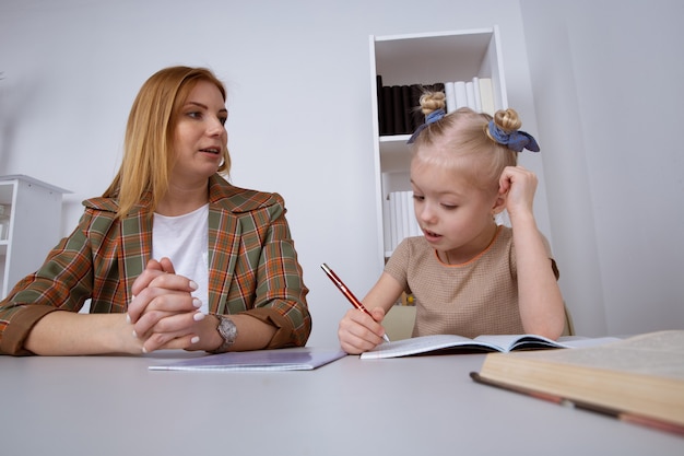 Faire des tâches et étudier le concept. Garde d'enfants avec une fille qui écrit ses devoirs.