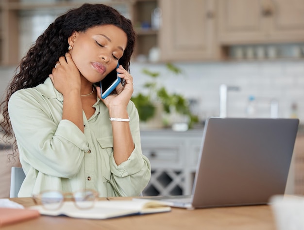 Faire tout ce qu'elle peut pour s'assurer qu'elle ne s'endette pas. Photo d'une jeune femme qui a l'air stressée en parlant sur un téléphone portable et en utilisant un ordinateur portable à la maison.