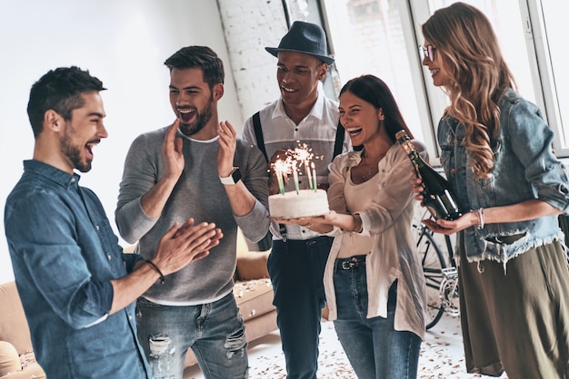 Faire un vœu! Heureux jeune homme célébrant son anniversaire entre amis