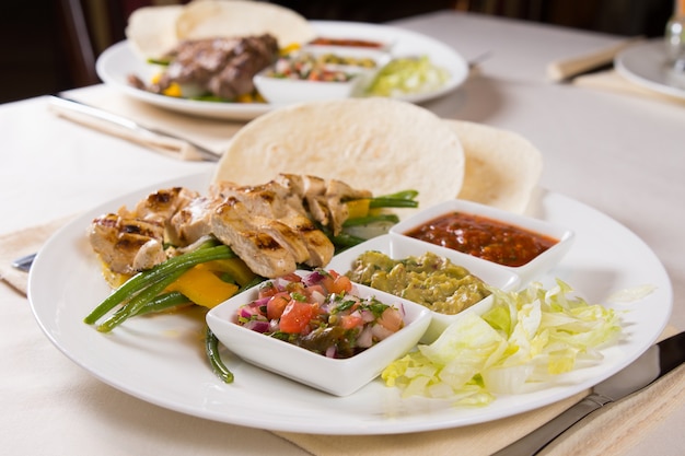 Fajitas au poulet grillé avec garnitures sur assiette servis au restaurant