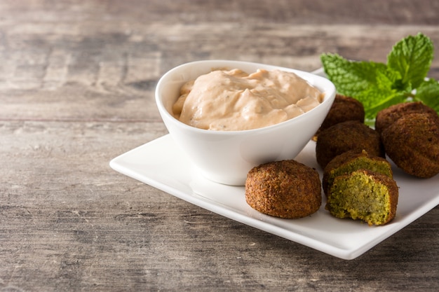 Falafel sur une assiette et sauce tahini sur table en bois