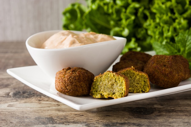 Falafel sur une assiette et sauce tahini sur table en bois