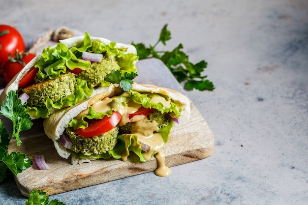 Falafel aux légumes frais et vinaigrette au tahini en pain pita sur le plateau. Concept de nourriture végétalienne saine.