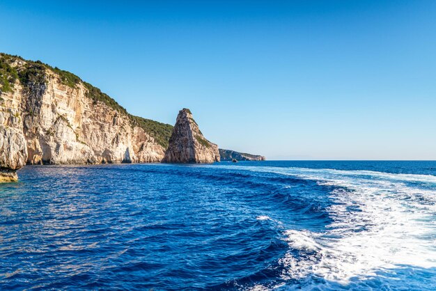 Falaises rocheuses en couches avec des plantes près du rivage de l'île de Corfou