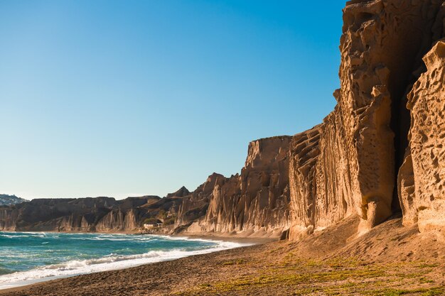 Des falaises volcaniques sur la plage de Vlichada, sur l'île de Santorin, en Grèce. Vue de la côte en journée ensoleillée.