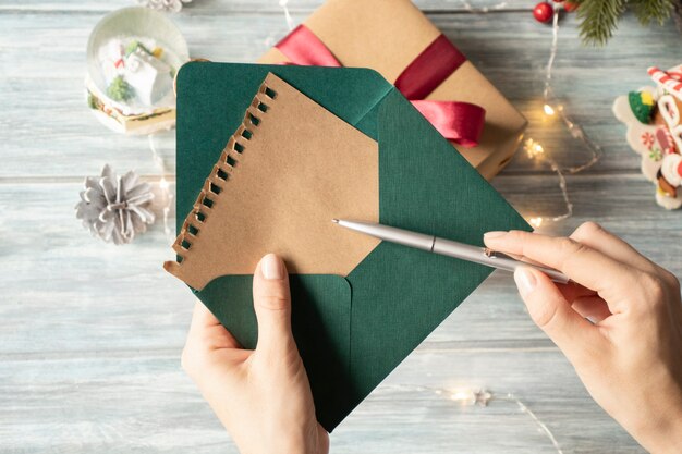Famale main écrit une lettre de Noël sur fond de bois