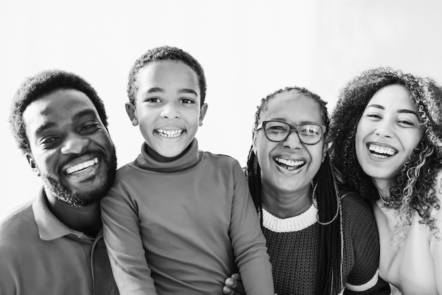 Famille africaine souriant devant une caméra intérieure à la maison Mise au point douce sur le visage droit de la mère Montage noir et blanc