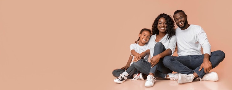 Photo une famille africaine souriante assise sur le sol sur un fond de studio jaune