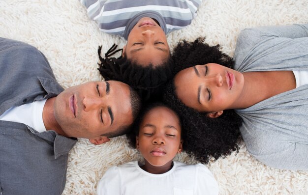 Famille afro-américaine dort sur le sol avec les têtes ensemble