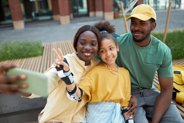 Photo famille afro-américaine faisant un portrait de selfie sur smartphone pendant leur promenade à l'extérieur