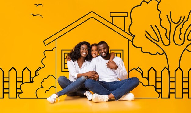 Photo famille afro-américaine mignonne père mère et fille assis dessinés sur le mur jaune de la maison