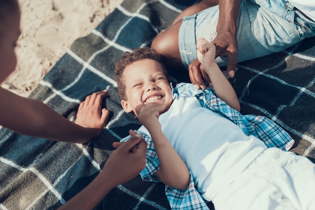 Famille afro-américaine se repose sur une couverture sur la plage de sable