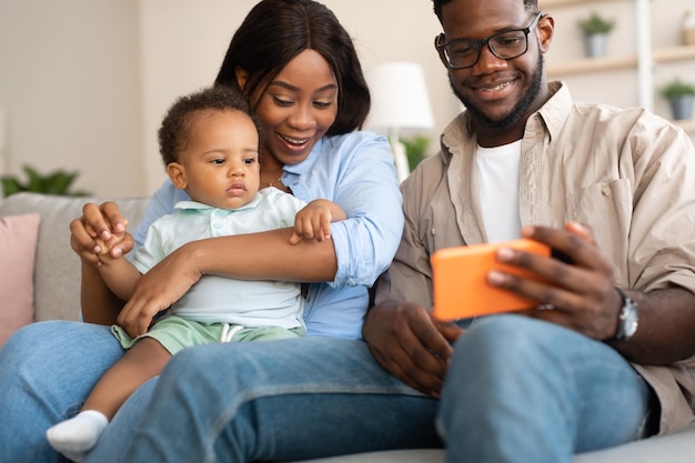 Famille afro-américaine utilisant un téléphone portable avec bébé à la maison