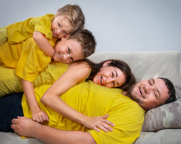 Photo la famille allongée sur le canapé l'une sur l'autre et riant