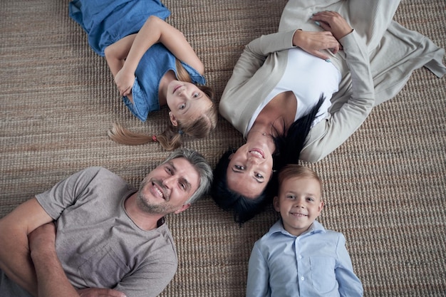 Famille allongée sur le sol avec la tête ensemble à la maison