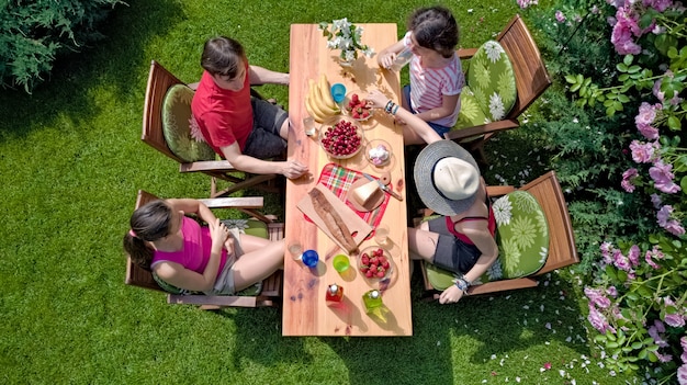 Famille et amis manger ensemble à l'extérieur sur garden-party d'été. Vue aérienne de la table avec de la nourriture et des boissons d'en haut. Concept de loisirs, vacances et pique-nique