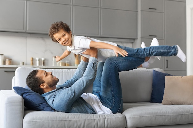 Famille amusante père noir heureux jouant avec son petit fils à la maison