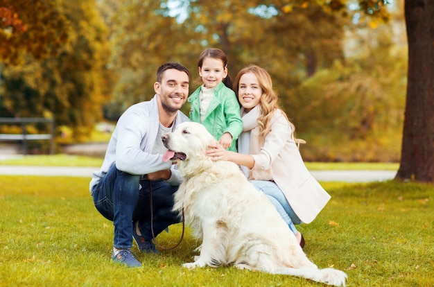 famille, animal de compagnie, animal domestique, saison et concept de personnes - famille heureuse avec chien labrador retriever en promenade dans le parc d'automne